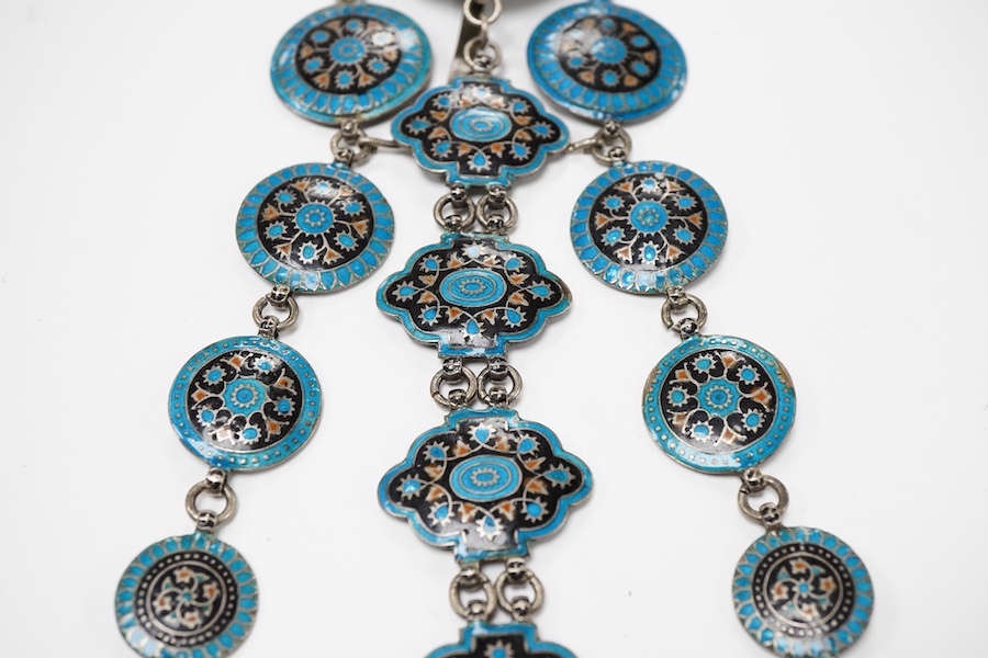 An enamel chatelaine, late 19th/early 20th century, composed of metal plaques applied with foliate patterns in blue, black and red enamel, indistinctly stamped maker's marks, suspending a silver pin cushion and a silver